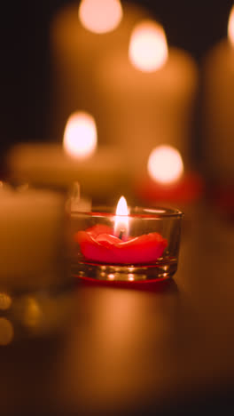 Vertical-Video-Close-Up-Of-Romantic-Lit-Red-And-White-Candles-Burning-On-Black-Background-With-Bokeh-Lighting-5